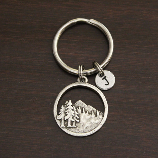 3 pine trees grouped together with mountains in the background keychain