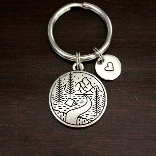 keychain with scene of river, pines, tent and mountains
